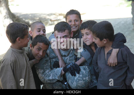 Afghan boys gather around a U.S. Army Soldier for a picture while talks with village elders are taking place. Members from Task Force Wolverine conducted a dismounted patrol through the Bagram Bazaar to find out information from the recent attack on Bargam Airfield, Parwan province, Afghanistan, May 24. Patrol through the Bagram Bazaar 283350 Stock Photo