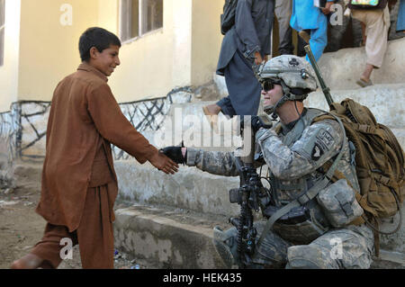 U.S. Army Spc. Andrew M. Dickerson, of Peoria, Ill., a radio telephone operator with 1st Platoon, Charlie Troop, 1st Battalion, 32nd Cavalry Regiment, Task Force Bandit, greets arriving school children in the Shamshir village in eastern Afghanistan’s Kunar province, June 14.  Soldiers from Forward Operating Base Bostick visit the school weekly to ensure the students and teachers are safe and have basic school supplies. (Photo by U.S. Army Spc. Albert L. Kelley, 300th Mobile Public Affairs Detachment) 1-32 Cavalry Ensures Education for the Young 292268 Stock Photo