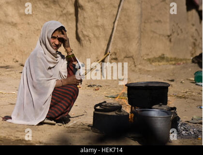 A young Afghan girl brings a pot of water to boil as she observes Afghan Soldiers with 3rd Commando Kandak, and U.S. Soldiers with Special Operations Task Force - South, in her village in Panjwa’i District, Oct. 26, 2010, in Kandahar Province, Afghanistan. (U.S. Army photo by Spc. Daniel P. Shook/Special Operations Task Force - South). Afghan Commandos, US Special Forces Find Firefights, IEDs in Panjwa'i 334744 Stock Photo