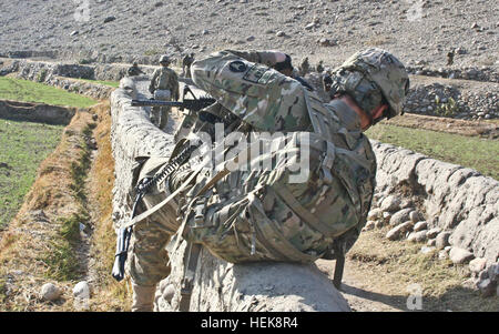 U.S. Army Spc. Michael Rupp, a radio telephone operator with Company C, 1st Battalion, 133rd Infantry Regiment, from Cherokee, Iowa, swings himself over a stonewall bordering a field outside the village of Tupac, Afghanistan, Jan. 21. After seven hours of dismounted searching through rugged terrain, Company C and their Afghan counterparts from Weapons Company, 1st Battalion, 201st Infantry Corps, located an improvised explosive device along Route Iowa, thanks to a tip from someone in the area of Tupac, Afghanistan. The soldiers had been struck by an IED in Tupac two days earlier. Fortunately,  Stock Photo