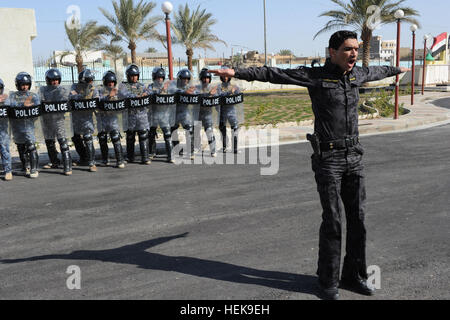 An Iraqi Police officer orders his riot team to get into a formation during a riot control training exercise in Ramadi, Iraq, March 3. U.S. soldiers assigned to the 442nd Military Police Company, New York National Guard, 4th Advise and Assist Brigade, 3rd Infantry Division assisted and instructed Iraqi police on riot control in support of Operation New Dawn. IP Riot Training 110303-A-TO648-010 Stock Photo