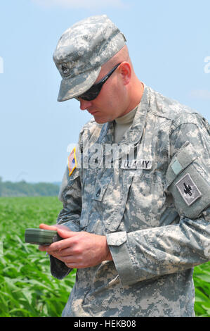 Staff Sgt. Brian Garr, Task Force 110 liaison officer for Andrew County from B Battery, 1/129th Field Artillery, Missouri Army National Guard uses a Defense Advanced GPS Receiver to help locate a position in a cornfield where a sand boil was reported to be.  Garr found two Sand Boils at the location. Sand boils occur when water under pressure wells up through a bed of sand. The water looks like it is 'boiling' up from the bed of sand, hence the name. Sand boils can be a sign that a levee is weakening, depending where they are located in relation to the levee and other factors. Missouri guardsm Stock Photo