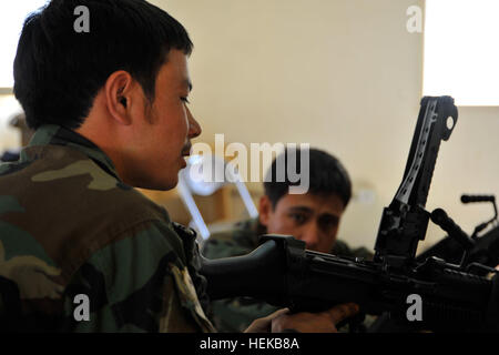 An Afghan National Army special forces recruit inspects the chamber of his assigned M249 machine gun, Kabul province, June 25. The recruits attend a four-phase course to be taught how to use different weapons, map reading, counter-insurgency, first aid and a variety of other military skills. (U.S. Army photo by Sgt. Lizette Hart) Afghan National Army special forces weapons training 421283 Stock Photo