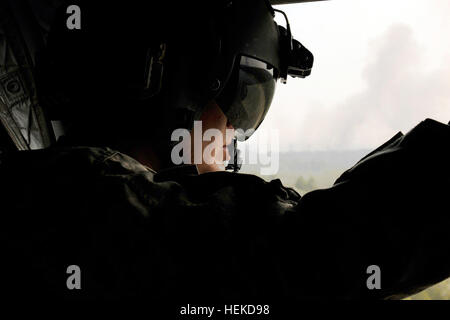 A CH-47 Chinook helicopter crew chief looks out toward the plume of smoke. Texas National Guard crews launched out of the Austin Army Aviation Facility to fight wild fires threatening homes and property near Bastrop, Texas, Sept. 6, 2011. Texas National Guard helicopters battle Bastrop blaze 110906-A-FG822-008 Stock Photo