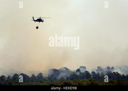 A Texas National Guard UH-60 Black Hawk dumps water over a wild fire. Texas National Guard crews launched out of the Austin Army Aviation Facility to fight wild fires threatening homes and property near Bastrop, Texas, Sept. 6, 2011. Texas National Guard helicopters battle Bastrop blaze 110906-A-FG822-013 Stock Photo