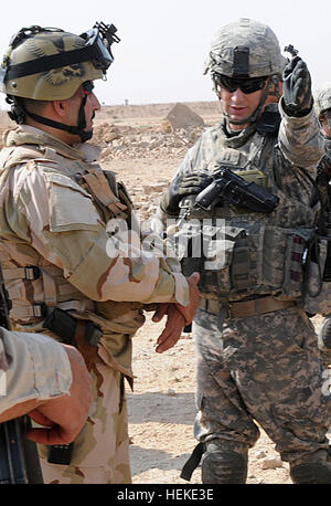 Capt. Scott Hinz, commander of the 2nd Brigade, 82nd Airborne Division's C Company, 1st Battalion, 325th Airborne Infantry Regiment, explains the aircraft's direction of flight to a 1st Iraqi Army Division lieutenant during an air-ground integration training exercise on a range in Fallujah, Iraq, Sept. 24. Forward observers assigned to C Company, 1-325th AIR, and truck drivers from the battalion's Forward Support Company, E Company, 407th Brigade Support Battalion, directed Apache helicopters to fire on an objective. This training familiarized the drivers with talking to the aircraft in case t Stock Photo