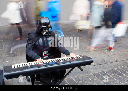 Darth Vader Busker proves Liverpool's music scene is out of this galaxy; Stormtrooper Costumes, Armour, Blasters, Holsters, Bodysuits, Neck Seals, Gloves, Boots with Christmas shoppers out in force at the 'Liverpool One' shopping precinct.  With mild winter temperatures & the festive season only a few days away, savvy shoppers took full advantage to buy their gifts in this upmarket area of Liverpool city centre UK Stock Photo