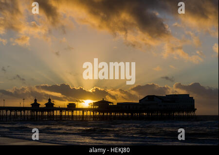 Blackpool, UK. 22nd Dec, 2016. The sun sets over Blackpool's North Pier on a bitterly cold day as a prelude to the forecast 'Storm Barbara', which is due to hit the UK tomorrow. The Met Office is expecting gusts of up to 90mph in places during the storm. ©Andy Gibson/Alamy Live News. Stock Photo