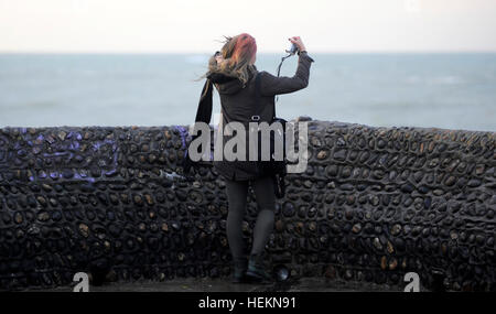 Brighton Sussex UK 23rd December 2016 - A young woman takes a selfie photogrpah on Brighton seafront as Storm Barbara is expected to hit Britain later today with winds forecast to reach up to 90 mph in Scotland  Photograph taken by Simon Dack Credit: Simon Dack/Alamy Live News Stock Photo