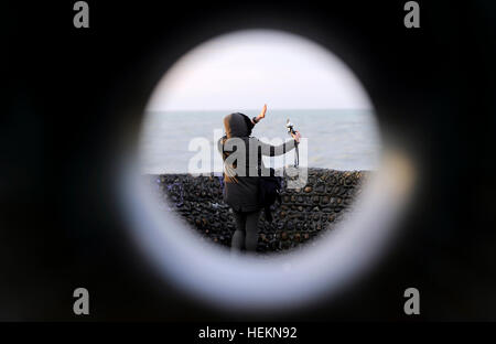 Brighton Sussex UK 23rd December 2016 - A young woman takes a selfie photogrpah on Brighton seafront as Storm Barbara is expected to hit Britain later today with winds forecast to reach up to 90 mph in Scotland  Photograph taken by Simon Dack Credit: Simon Dack/Alamy Live News Stock Photo