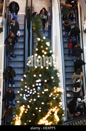 Frankfurt, Germany. 23rd Dec, 2016. People on an escalator passing by an illuminated Christmas tree at the 'MyZeil' shopping centre in Frankfurt, Germany, 23 December 2016. Many people are using the final hours before Christmas Eve to buy their last gifts. Photo: Arne Dedert/dpa/Alamy Live News Stock Photo