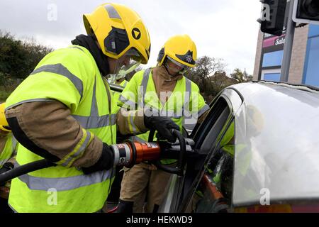 Firefighter cutting the roof off a car at the scene of an accident demonstration, UK. 'Car crash' scene, RTA or RTC, Crashed car with firemen work Stock Photo