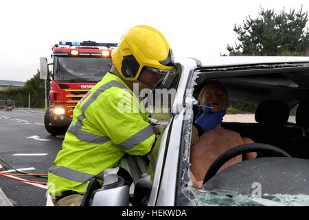 Firefighters working at the scene of an accident demonstration, UK. 'Car crash' scene, RTA or RTC, Crashed car with firemen work Stock Photo