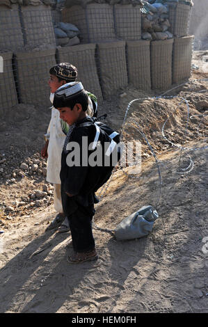 Two young Afghan boys wait for their parents to walk them home after attending an open house at a school near Forward Operating Base Howz e Madad, Nov. 26. The backpacks they are wearing were gifts from the open house, filled with school supplies for them to use. Afghan boys receive backpacks and school supplies from school open house 489694 Stock Photo