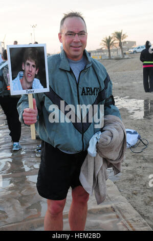 Command Sgt. Maj. Bruce Stowe, from the 1/34 Brigade Special Troops Battalion, 1st Brigade Combat Team, 34th Infantry Division and a Northfield, Minn., native, holds a photo Tyler, his daughter's neighbor, after he jumped into a pool of ice with water during a Polar Bear Plunge held at Camp Arifjan, Kuwait, Feb. 4. Stowe ran a 5K in honor of Tyler before jumping in the bath of ice water. Minnesota Polar Bear Plunge in Kuwait 120204-A-NN423-136 Stock Photo