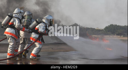 Royal Thai air force fire fighters spray water over gasoline during a fire rescue and medical safety demonstration held in support of Exercise Cobra Gold 2012 at Wing One Royal Thai air force base, Nakhon Ratchasima, Kingdom of Thailand, Feb. 9, 2012. The demonstration consisted of joint efforts in fire rescue and medical safety procedures by participating nations in CG 12. The exercise improves the capability to plan and conduct combined joint operations, building relationships between partnering nations and improving interoperability across the Asia-Pacific Region. Exercise Cobra Gold 2012 1 Stock Photo