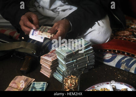 A local Afghan elder counts money for the local militia commander to pay to his men, during a key leaders engagement inside an Afghan Uniformed Police compound, in the Dur Baba district, Nangarhar province, Afghanistan, Feb. 13, 2012. Soldiers serving with the 549th Military Police Company, Task Force Raider conducted a key leaders engagement with the Dur Baba district sub-governor to discuss the closing of the local militia program. Afghan Uniformed Police ANA patrol 120213-A-LP603-114 Stock Photo