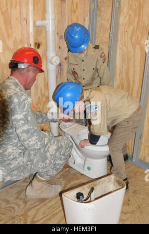 Sgt. Dennis Halvorsen, an instructor with the 164th Regional Training Institute, assists 10-year-old Gabe Marx, and 11-year-old Caedmon Venderdahl, both of Bismarck, in assembling a toilet and attaching it to water pipes as a part of their Boy Scout merit badge training. Three troops of about 30 Boy Scouts from Bismarck and Fargo, N.D., traveled to Camp Grafton in Devils Lake this weekend to receive merit badge training from the soldiers of the Regional Training Institute (RTI) this weekend. Volunteer soldiers from the North Dakota National Guard's (NDNG)  164 Regional Training Institute instr Stock Photo