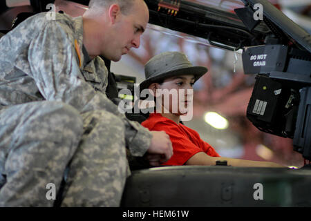 (from left) Chief Warrant Officer Frank Capri and Capt. Joseph Sinkiewicz, pilots assigned to B Company, 1st Battalion, 10th Combat Aviation Brigade, show a pair of Boy Scouts the cockpit of the Apache helicopter at Wheeler-Sack Airfield, May 12. The Boy Scouts were visiting for the weekend to get a taste of Army life and celebrate the values shared by the Boy Scouts and America's military. 1-89 CAV hosts Boy Scout visit to Fort Drum 051212-A-EB125-053 Stock Photo