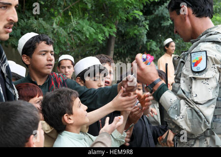 An Afghan Border Police (ABP) officer, right, passes out candy and other treats to Afghan children in Ayub Khel, Khost province, Afghanistan, Sept. 8, 2012. U.S. Soldiers with Team Hatchet, 1st Battalion, 501st Infantry Regiment, Task Force 4-25 and the ABP set up a security checkpoint in the village to speak with passing motorists. (U.S. Army photo by Sgt. Kimberly Trumbull/Released) Security checkpoint 120908-A-PO167-077 Stock Photo