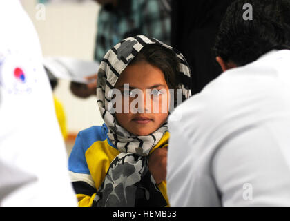 A young Afghan girl rolls up her sleeve and waits patiently to receive an immunization shot from an Afghan male nurse in Charikar, Afghanistan, Oct. 18, 2012. The girl and several other Afghan children are students in a small school run by South Korean volunteers and Afghan instructors. Koreans prepare to leave legacy to Afghanistan 121018-A-XO441-060 Stock Photo