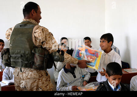 A smiling Iraqi boy receives a bag of school supplies from an Iraqi army soldier during a joint humanitarian aid mission at an elementary school in Um Najim, Feb. 22 with Company C, 2nd Battalion, 23rd Infantry Regiment, 4th Stryker Brigade Combat Team, 2nd Infantry Division. IA, U.S. participate in humanitarian aid mission for school children 256803 Stock Photo