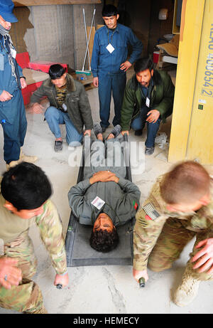Afghan National policemen and U.S. Army Soldiers with the Texas Army National Guard prepare to lift a simulated casualty during combat first aid training at Forward Operating Base Hadrian, Deh Rawud district, Uruzgan province, Afghanistan, Feb. 13, 2013. During the past two months, 21 policemen in Deh Rawud district have been trained in Combat Life Saver first aid by Soldiers with the 56th Infantry Brigade Combat Team Police Security Force Advisor Team and now one of the Afghan patrolmen has stepped up to train his fellow officers. (Courtesy Photo) Afghan Police medic steps up training in Deh  Stock Photo