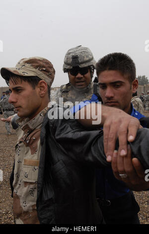 Staff Sgt. Faaaoga Ena, center, the Headquarters and Headquarters Company commander's gunner with 2nd Battalion, 23rd Infantry Regiment teaches an Iraqi policeman how to search personnel using an Iraqi army soldier near the Taji Bridge, Feb. 26 during combined training for IA and IPs. Ena, a native of American Samoa, is currently serving in Operation Iraqi Freedom with 4th Stryker Brigade Combat Team, 2nd Infantry Division. Iraqi army, Iraqi police work together during Tiger Team training 260358 Stock Photo