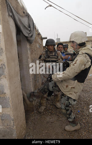 An Iraqi army soldier kicks in the door to a building on an IA compound near the Taji Bridge, Feb. 26 during a culmination search and patrol exercise. Soldiers from the Mobile Tiger Team with 2nd Battalion, 23rd Infantry Regiment, 4th Stryker Brigade Combat Team, 2nd Infantry Division taught IA and IP how to search personnel, vehicles and clear buildings at a three-day training class. Iraqi army, Iraqi police work together during Tiger Team training 260360 Stock Photo