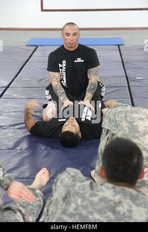 Modern Army Combatives Program Level 1 instructor, Staff Sgt. Frank 'Ricky' Rodriguez, shows a mount position during a block of instruction on Tuesday, March 5, 2013, at Camp Arifjan, Kuwait. Rodriguez, a motor transport operator with the 47th Transportation Company, has been teaching the combatives course since 2009. U.S. Army photo by Sgt. 1st Class Tina R. Eichenour, 38th Sustainment Brigade Combatives level, Army 130305-A-RW051-153 Stock Photo