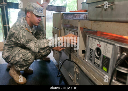 FORT INDIANTOWN GAP, Pa. - Pfc. Kyle C. Landry, a chemical, biological, radiological and nuclear explosive specialist with the 254th QM Co.; replaces a burner unit in the mobile kitchen trailer during the Connelly Competetion due to low flame output. (US Army photo by Sgt. Michael T. Crawford) Army Reserve cooks turn drill into competition 130622-A-JH560-001 Stock Photo