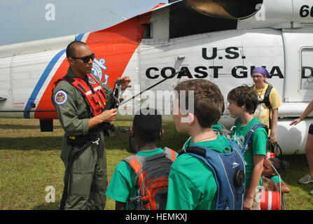 At left, Coast Guard Petty Officer 2nd Class Mario Estevane, a rescue swimmer with ATC-Mobile, demonstrates rescue equipment for Kids AT campers at the 'Air Guard Day' event held on the Camp Shelby Air-to-Ground Range June 27. Kids AT 2013 130627-A-FQ119-004 Stock Photo