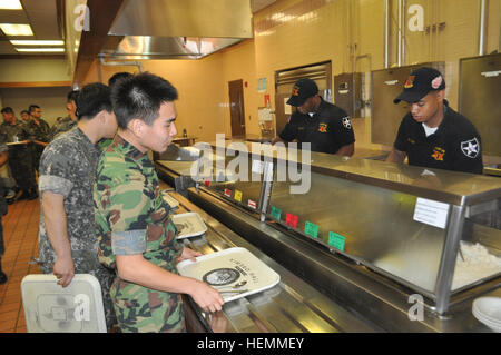 U.S. soldiers and soldiers from Third Republic of Korea Army line up for lunch in Thunder Inn Dining Facility during a Combined Counterfire Exercise on Camp Casey July 18, 2013. The simulation-based exercise is to enhance the ROK-U.S. counterfire capability, improve staff coordination, and test battle command systems. The 210th Fires Bde. trains with its ROK partners to strengthen the alliance and ensure it is ready to 'Fight Tonight' to deter any threats toward the Republic of Korea. (U.S. Army photo by Cpl. Kim Han-byeol, 210th Fires Brigade public affairs specialist/Released). ROK-US Combin Stock Photo