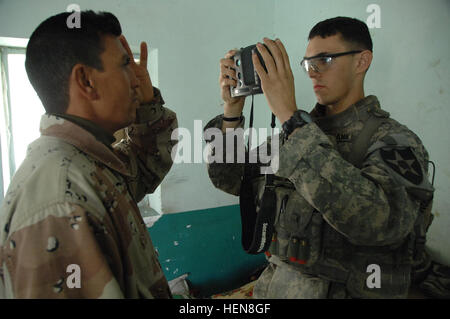 A U.S. Army Soldier from Alpha Company, 2nd Battalion, 23rd Infantry Regiment, 4th Brigade Combat Team, 2nd Infantry Division scans the eye of an Iraqi man into the Hand Held Inter-agency Identity Detection Equipment system for registration, Muqdadiyah, Iraq, Jan. 25, 2008. (U.S. Army Photo/Spc. Shawn M. Cassatt) Aco conducts Concerned Local Citizen registration and Co-op Humanitarian Aid with IP and CLC in Nowfal. 75482 Stock Photo