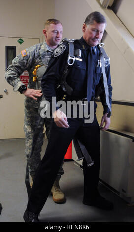 U.S. Army Sgt. 1st Class Garret Brunton, the S3 air operations noncommissioned officer in charge for the 4th Infantry Brigade Combat Team (Airborne), 25th Infantry Division, helps the Anchorage City chief of police, Mark Mew, don a T-11 parachute during 'The Paratrooper Experience' community partnership day Nov. 13, 2013 at Joint Base Elmendorf-Richardson, Alaska. Brunton explained how Army jumpmasters and paratroopers ensure strict safety measures are taken to ensure proper and safe airborne operations. (U.S. Army photo by Staff Sgt. Jeffrey Smith/Released) Spartans invite Alaskan leaders to  Stock Photo