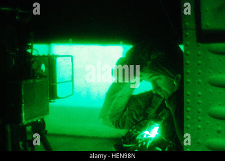 As seen through a night vision lens, U.S Army Sgt. Benjamin McLaughlin, a UH-60M Black Hawk helicopter crew chief assigned to C Company 'War Lords', 2nd Battalion (Assault), 10th Combat Aviation Brigade, Task Force Knighthawk, dons his cold-weather gear prior to a night personnel movement mission Dec. 4, at Forward Operating Base Shank, Afghanistan.  (U.S. Army Photo by Capt Peter Smedberg/Released) Night flight operations 131204-A-MH207-689 Stock Photo