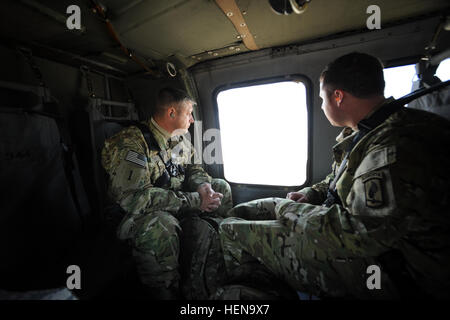 Retired Command Sgt. Maj. James Champagne, left, and Cpl. Jesse Murphree, a medically retired infantryman, fly in a Black Hawk helicopter to Camp Buehring, Kuwait, Dec. 18. Murphree and four other wounded warriors visited Kuwait before their trip to Afghanistan in support of Operation Proper Exit, a Troops First Foundation mission that takes wounded warriors back into theater. Operation Proper Exit, Wounded warriors return to find closure 131217-A-TG995-011 Stock Photo