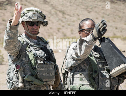 FORT IRWIN, Calif. - A U.S. Army noncommissioned officer, assigned to 977th Military Police Company, 97th Military Police Battalion, 1st Infantry Division, directs his Soldier to the checkpoints while flying an AeroVironment RQ-11 Raven prior to launch during a training operation at the National Training Center, April 19, 2014. The Raven is a small hand-launched remote- controlled unmanned aerial vehicle (UAV) used to show higher command a birds eye view of a specific terrain.  (U.S. Army photo by Sgt. Richard W. Jones Jr., Operations Group, National Training Center) National Training Center R Stock Photo