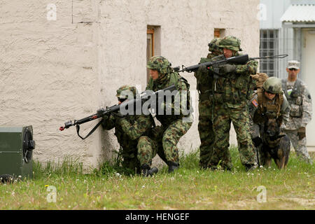 Lithuanian soldiers provide a security escort for Sgt. Kara Yost, a Military Police dog handler with the 131st Military Working Dog Detachment, 615th Military Police Company during urban assault training on Hohenfels Army base during the multi-national training exercise, Combined Resolve II. MWD security 140517-A-SJ786-014 Stock Photo