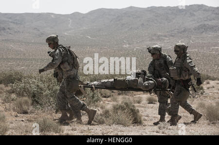 FORT IRWIN, Calif. –  U.S. Army Soldiers, assigned to Charlie Troop, 2nd Battalion, 11th Field Artillery Regiment, carry a wounded Soldier to a vehicle during Decisive Action Rotation 14-07 at the National Training Center, May 17, 2014. The two-week training rotation provides a live, virtual, and constructive training environment, allowing units to fully exercise their tactical and technical skill-set. (U.S. Army photo by Sgt. Richard W. Jones Jr., Operations Group, National Training Center) Soldiers engage enemy targets with howitzer 140517-A-QU939-521 Stock Photo