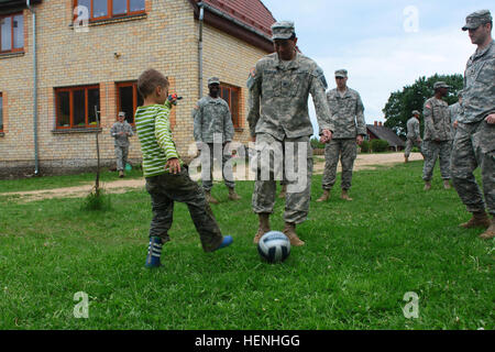 U.S. Army Staff Sgt. David Figueroa, a paratrooper assigned to the 173rd Airborne Brigade based out of Vicenza, Italy, plays soccer with a child from the Zvanninieki Alternative Family Home May 30, 2014, during a multinational community outreach event in Vaive, Latvia. Soldiers from the 173rd Airborne and the 500th Engineer Company, based out of Grafenwoehr, Germany, collected and split firewood, constructed the foundation for a barn and dug a trench to supply clean water as part of the event, which was organized by the U.S. Embassy in Latvia. (U.S. Army photo by Sgt. Alonzo Werner, 173rd Airb Stock Photo