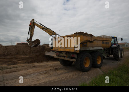 A wheeled excavator operated by Belgian contractors digs the ground around a former jet fuel storage site on Chièvres Air Base in order to remove, test, and if needed, decontaminate the soil in Chièvres, Belgium, June 20, 2014. The work is coordinated between the Corps of Engineers, the Environmental Division, Department of Public Works, United States Army Garrison Benelux, and the Belgian Ministry of Defense. (U.S. Army photo by Visual Information Specialist Pierre-Etienne Courtejoie-Released) POL decontamination USAG Benelux 140620-A-BD610-031 Stock Photo