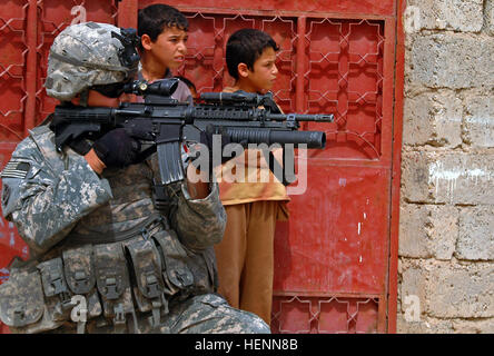 As Iraqi children peek out their front gate Spc. Vencent Hashimoto, an infantryman in 1st Platoon, Company D, 1st Battalion, 8th Infantry Regiment from Fort Carson, Colo., scans his surroundings during a combat patrol in  Mosul, Iraq, on April 12. Infantry Soldiers recon Mosul 84770 Stock Photo