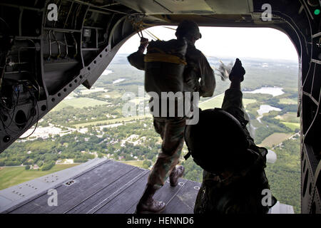 A South African paratrooper jumps off the tailgate of a CH-47 Chinook helicopter during a familiarization jump at the Leapfest Airborne Competition July 30, 2014, in West Kingston, R.I. Leapfest is an airborne parachute competition sponsored by the Rhode Island National Guard to promote high level technical training within the international airborne community. (U.S. Army photo by Sgt. Austin Berner/Released) Leapfest 2014 140730-A-BZ540-116 Stock Photo
