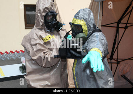 Sgt. Bajram Peci, left, leader decontamination station, 1st Platoon, Hazmat Company, Civil Protection Regiment, Kosovo Security Force, removes a chemical protection suit from Staff Sgt. Wendell Reeder, survey team chief, 773rd Civil Support Team, 7th Civil Support Command, and a native of Atlanta, during a Defense Threat Reduction Agency-sponsored preparedness partnership exercise on Panzer Kaserne Aug. 20, 2014. 7th CSC Soldiers train Kosovo Security Force HAZMAT Company 140820-A-NP785-009 Stock Photo