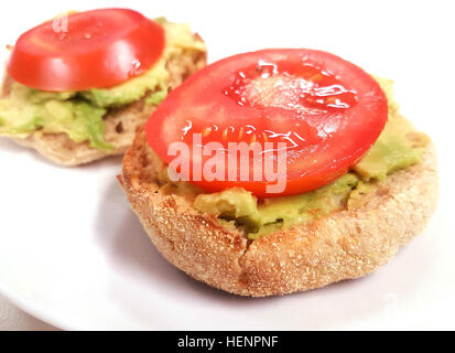 fast and easy delicious English muffins with spread avocado and tomato on top Stock Photo