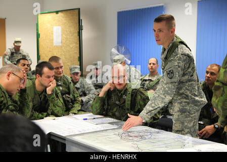 An U.S. Soldier of 500th Engineer Company, 15th Engineer Battalion, references a map while coordinating with Lithuanian soldiers of 'Iron Wolf' Mechanized Infantry Brigade to plan a mission during training exercise Saber Junction 2014 at the Joint Multinational Readiness Center in Hohenfels, Germany, Sept. 6, 2014. Saber Junction 2014 prepares U.S., NATO allies and European security partners to conduct unified land operations through the simultaneous combination of offensive, defensive and stability operations appropriate to the mission and the environment. More information about Saber Junctio Stock Photo
