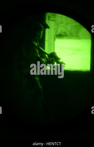 A soldier, from 1st Battalion, 10th Special Forces Group, watches from a window during the special operations training, Jackal Stone 2014, seen through night vision, while at Wiesbaden Training Support Center’s Urban Operations site at the Mainz-Finthen Local Training Area.   Exercise Jackal Stone is a U.S. Special Operations Command Europe-led exercise which supports and enhances established professional military-to-military relationships and builds new ones among participating nations’ militaries by sharing doctrinal concepts, training concepts and tactics, according to the U.S. European Com Stock Photo