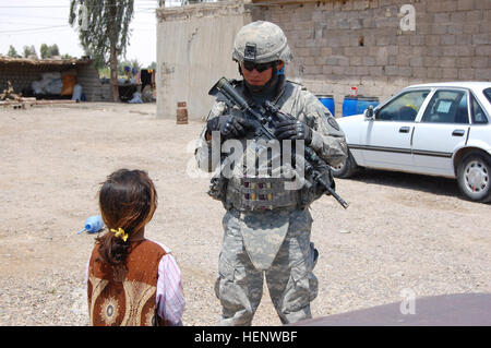 Spc. Austin Sandoval, a Lukachukai, Ariz., native, talks with an Iraqi girl while on patrol the East Anbar province, northwest of Baghdad, May 11. Sandoval is a mortarman assigned to Headquarters and Headquarters Company, 1st Battalion, 27th Infantry Regiment 'Wolfhounds,' 2nd Stryker Brigade Combat Team 'Warrior,' 25th Infantry Division, Multi-National Division - Baghdad. (U.S. Army photo/Staff Sgt. J.B. Jaso III) Securing safe place for Iraq's future 88834 Stock Photo