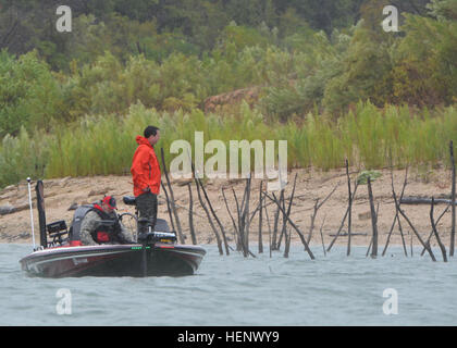 A rain-soaked team of anglers brave the elements in the hopes of winning the 1st place prize, a new bass boat, during the Fishing for Freedom fishing tournament held at Belton Lake Outdoor Recreation Area Oct. 11. The 9th annual tournament pairs Texas boat owners with current and former military members in a one-day tournament in a spirit of mutual passion for the outdoors. (U.S. Army photo by Sgt. Brandon Anderson 13th Public Affairs Detachment/Released.) Fishermen brave elements during 9th Annual Fishing for Freedom Tournament 141011-A-PU919-082 Stock Photo